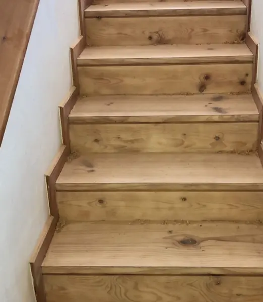 Peldaños lijados, con la madera viva a la vista y restos de serrín