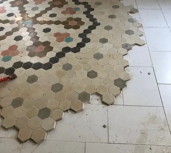 Mosaico hidráulico hexagonal original, con el porcelánico de alrededor ya retirado en parte