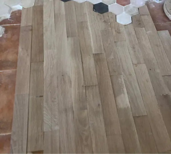 Tablas de roble recién colocadas junto al borde del mosaico