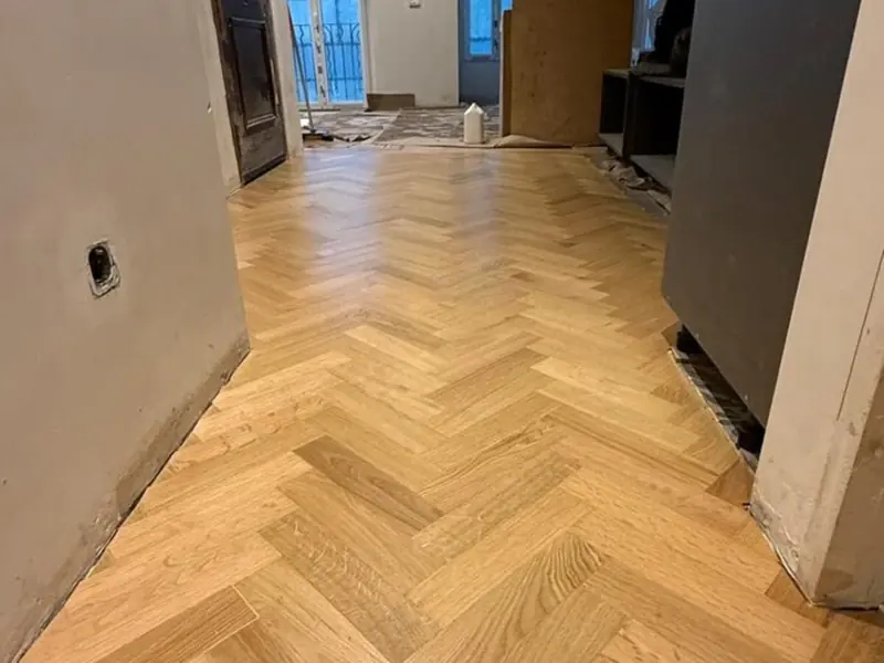 Pasillo terminado en espiga de roble que se abre hacia el salón
