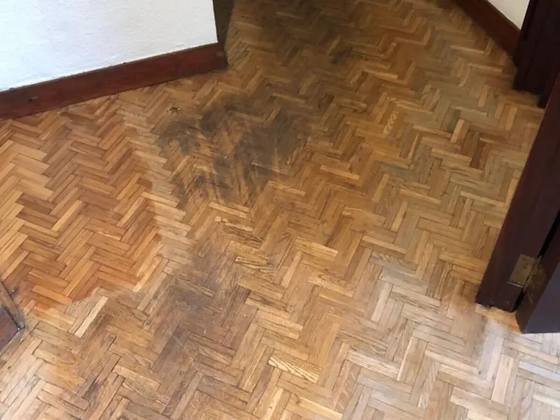 Parquet en espiga con manchas oscuras y el barniz desgastado