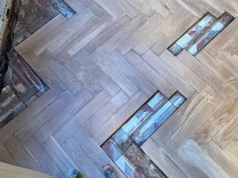 Parquet en espiga con huecos de tablillas perdidas y la baldosa antigua a la vista
