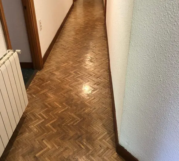 Pasillo con el parquet apagado y desgastado antes de la restauración